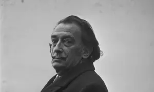 Salvador Dalí, z charakterystycznym wąsem i spojrzeniem, w płaszczu. Ciekawe fakty o jego życiu i sztuce.