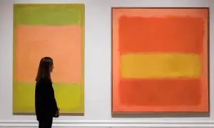 Kobieta podziwia dwa abstrakcyjne obrazy Marka Rothko. Jeden z nich, z dominującymi kolorami zieleni i brzoskwini, jest uznawany za najdroższy obraz tego artysty.