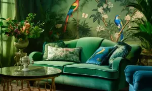 Luksusowy salon w stylu secesji. Zielona sofa, tapeta z ptakami i kwiatami, stolik kawowy. Obrazy secesyjne tworzą atmosferę.