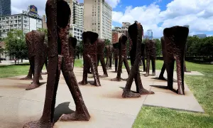 Rzeźby Magdaleny Abakanowicz, grupa bezgłowych postaci w brązie, stoi na placu w mieście.