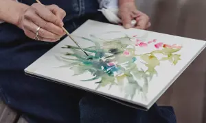 Artysta tworzy akwarelowy obraz kwiatów, zastanawiając się, jakie obrazy najlepiej się sprzedają.