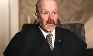 Portret starszego mężczyzny z siwą brodą i wąsami, w garniturze i krawacie. Jego spojrzenie jest intensywne, jakby uchwycone w chwili głębokiej refleksji nad rzeczywistością. Malczewski w swoim żywiole.