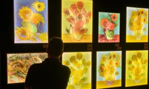 Osoba ogląda wystawę obrazów van Gogha z słonecznikami.