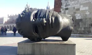 Gigantyczna, metalowa głowa leży na cokole. To intrygująca rzeźba, która przyciąga wzrok przechodniów na rynku.