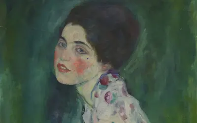 Portret kobiety z niebieskimi oczami i rumieńcami, w kwiecistej sukni. Oryginalne obrazy Klimta zachwycają.