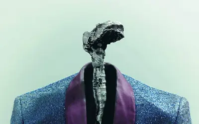 Srebrzysta, nieregularna forma na tle błękitnej, błyszczącej marynarki z fioletowym kołnierzem. Czy to symbol performers, co to znaczy?