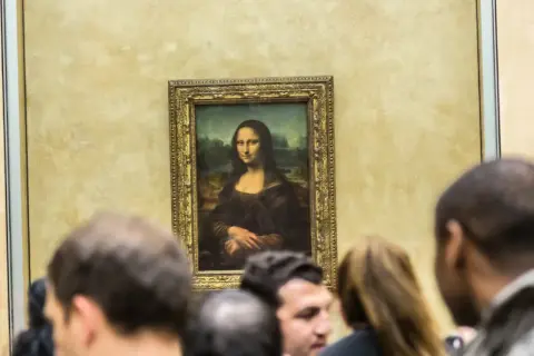 Słynny obraz Mona Lisa da Vinci, otoczony tłumem widzów w muzeum.