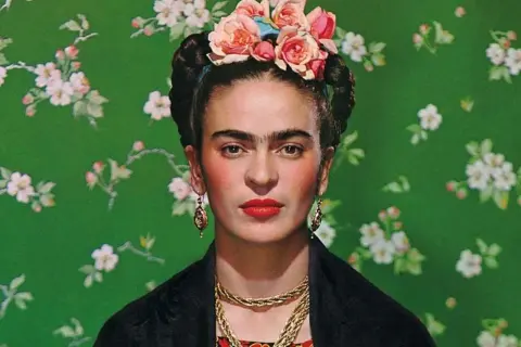 Frida Kahlo, symbol siły mimo niepełnosprawności, w kwiecistej opasce i z wyrazistym spojrzeniem.