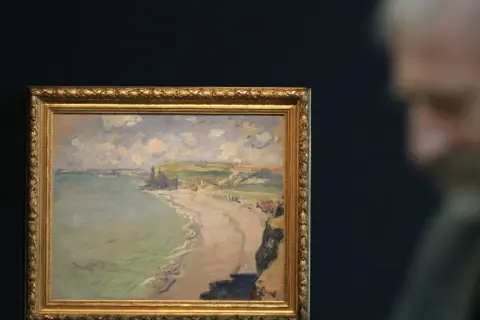 Obraz przedstawia plażę w Pourville, z klifami i morzem w tle. W oddali widać sylwetkę mężczyzny.