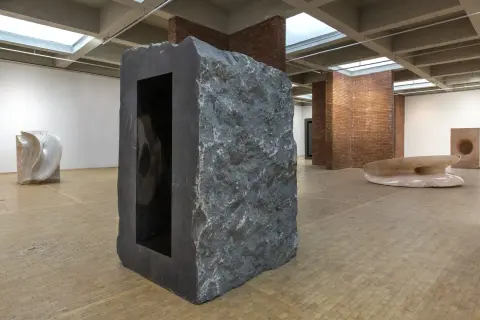 Kamienna rzeźba z czarnym wnętrzem, część wystawy Anish Kapoor w Orońsku. W tle inne dzieła sztuki.