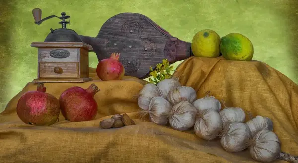 Martwa natura przykłady: czosnek, granaty, cytryny, młynek do kawy i miech.