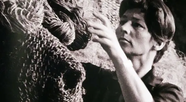 Magdalena Abakanowicz z dłońmi wśród swoich monumentalnych, plecionych dzieł, abakanów.