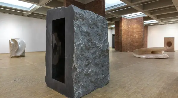 Kamienna rzeźba z czarnym wnętrzem, część wystawy Anish Kapoor w Orońsku. W tle inne dzieła sztuki.
