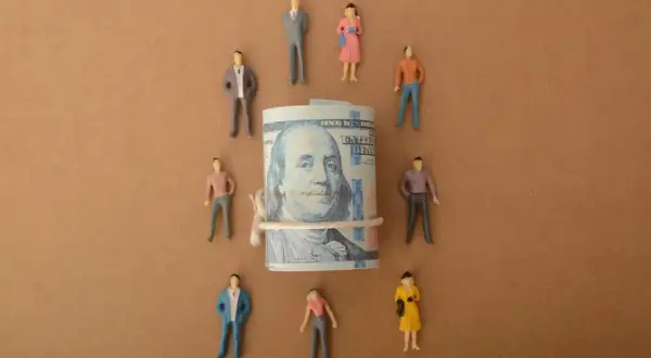 Figurki ludzi otaczają zwinięty banknot stuzłotowy. Symbolizuje to, jak mecenas sztuki wspiera artystów, finansując ich twórczość.