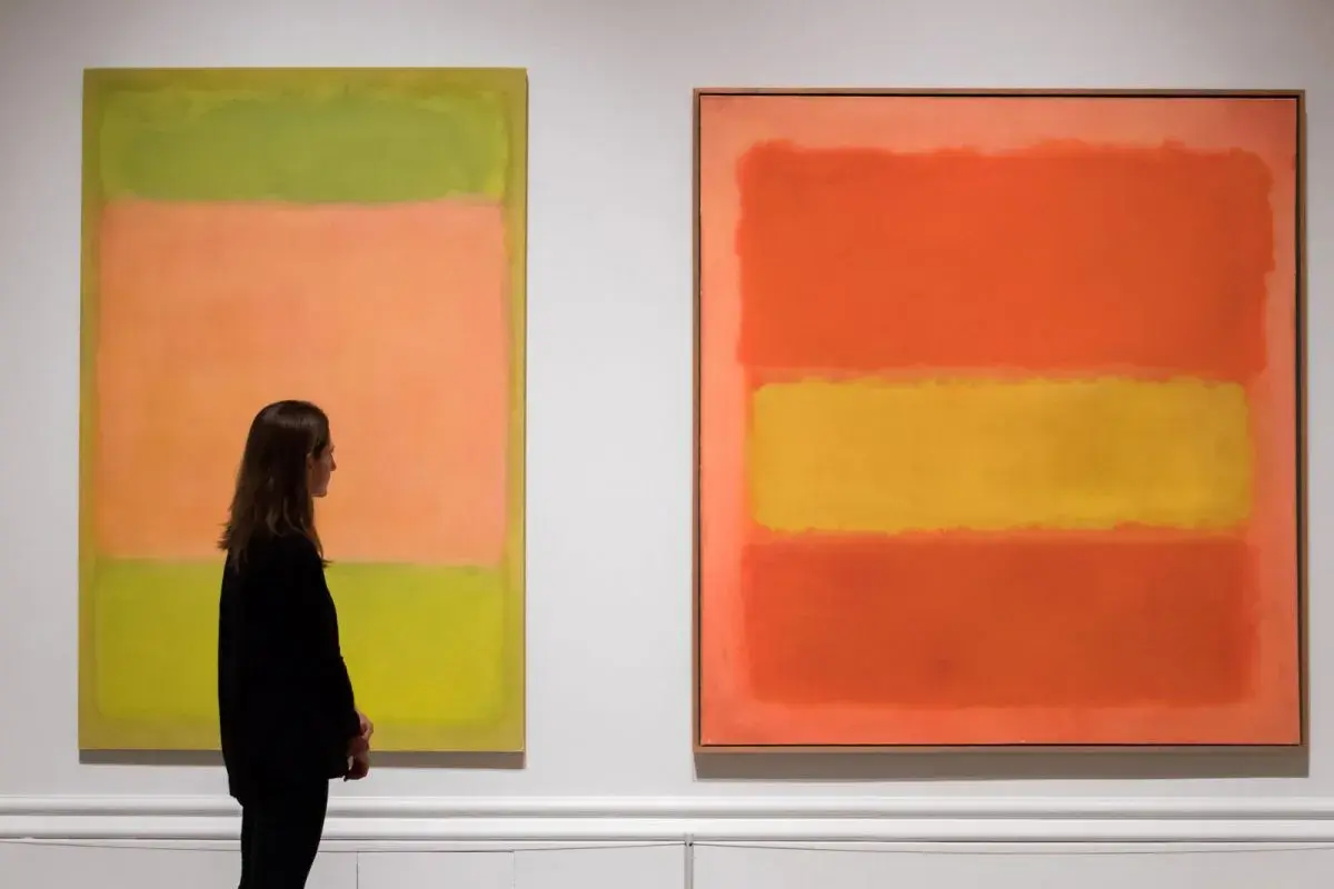 Kobieta podziwia dwa abstrakcyjne obrazy Marka Rothko. Jeden z nich, z dominującymi kolorami zieleni i brzoskwini, jest uznawany za najdroższy obraz tego artysty.