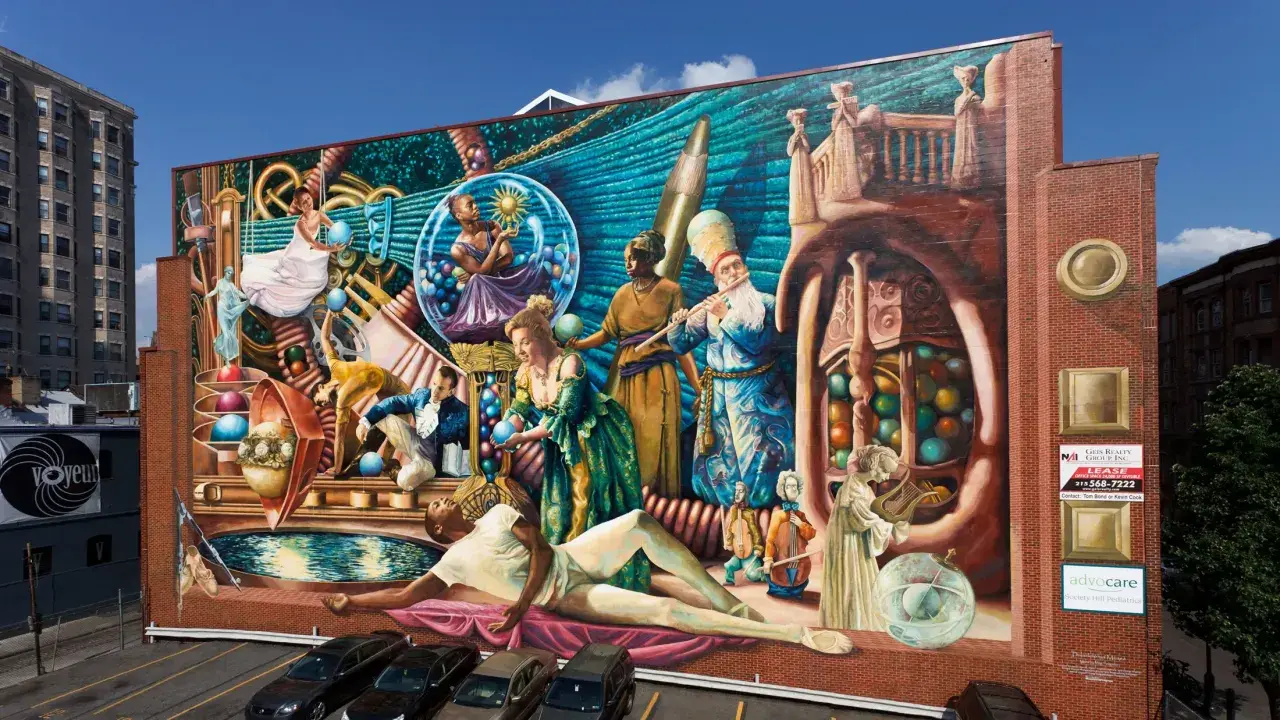 Wielobarwny mural przedstawia surrealistyczną scenę z ludźmi w historycznych strojach, kulami i instrumentami.