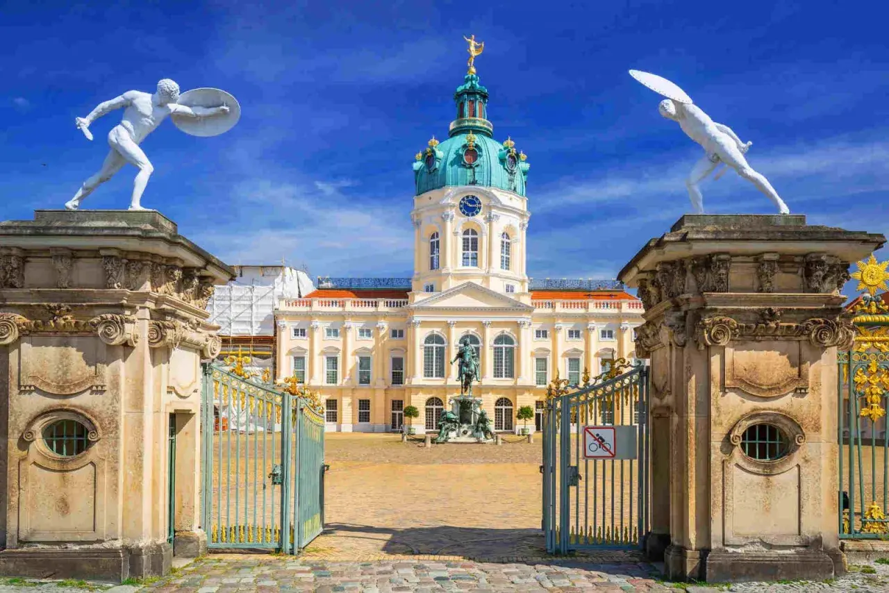 Pałac Charlottenburg w Berlinie, z jego kopułą i bogatymi zdobieniami, zachwyca w stylu na końcu baroku. Dwie białe rzeźby wojowników strzegą wejścia.