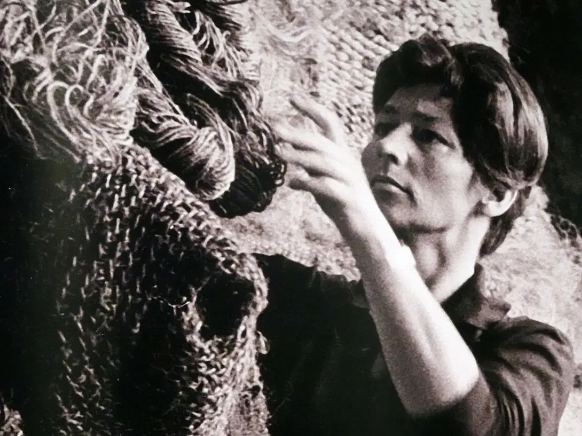 Magdalena Abakanowicz z dłońmi wśród swoich monumentalnych, plecionych dzieł, abakanów.