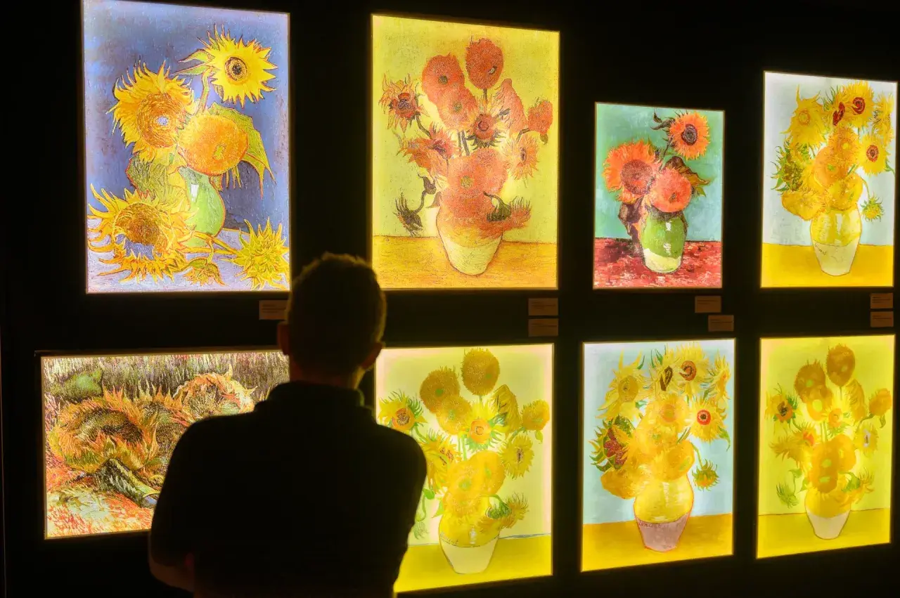 Osoba ogląda wystawę obrazów van Gogha z słonecznikami.