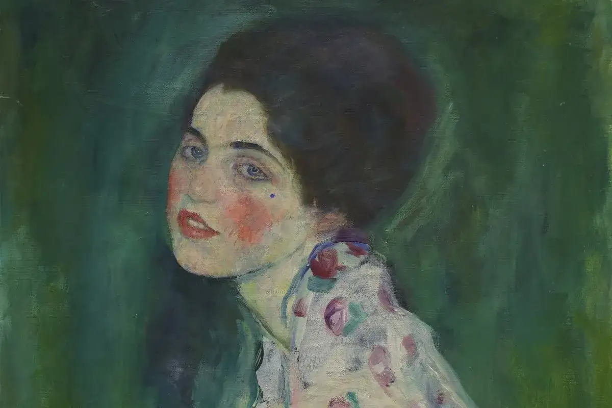Portret kobiety z niebieskimi oczami i rumieńcami, w kwiecistej sukni. Oryginalne obrazy Klimta zachwycają.