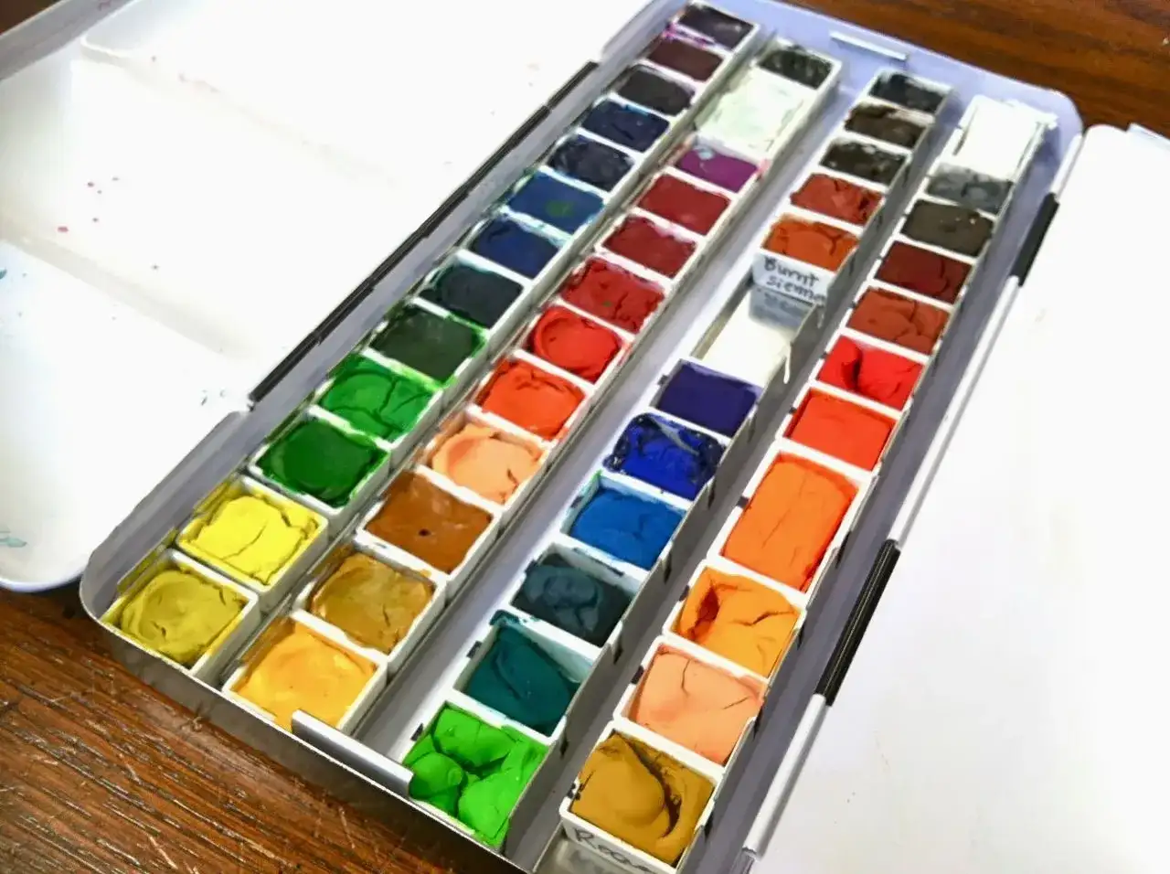 Paleta farb akwarelowych, w tym odcień "Burnt Sienna". To świetny zestaw do malowania, który pokazuje, co to jest gwasz.