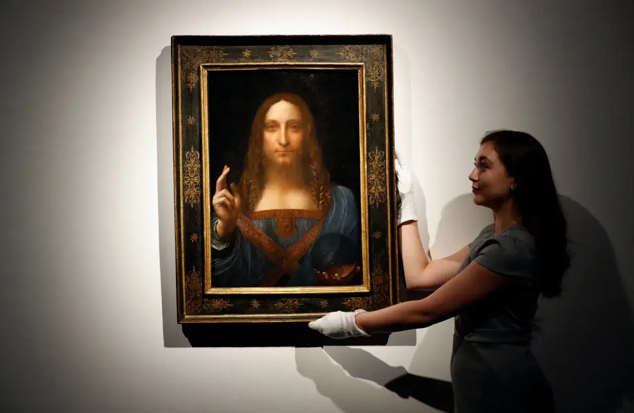 Obraz Salvator Mundi, uznawany za najdroższy obraz na świecie, prezentowany przez pracownika muzeum.