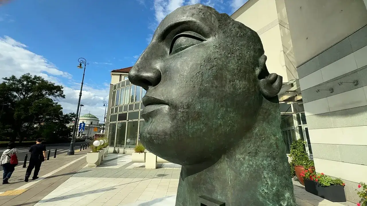 Monumentalna głowa z brązu, jedno z dzieł Igora Mitoraja, góruje nad miejskim placem.