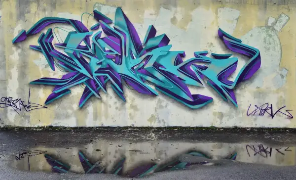 Wielobarwne, przestrzenne graffiti w odcieniach turkusu i fioletu zdobi ścianę. To przykład sztuki ulicznej, która często jest formą wyrazu artystycznego.