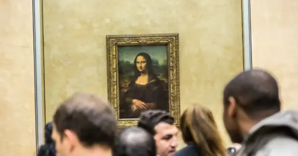 Słynny obraz Mona Lisa da Vinci, otoczony tłumem widzów w muzeum.