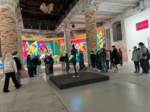 Grupa zwiedzających ogląda barwne instalacje w galerii. To właśnie jest biennale – świat sztuki w pigułce.