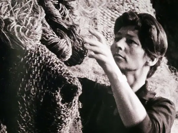 Magdalena Abakanowicz z dłońmi wśród swoich monumentalnych, plecionych dzieł, abakanów.
