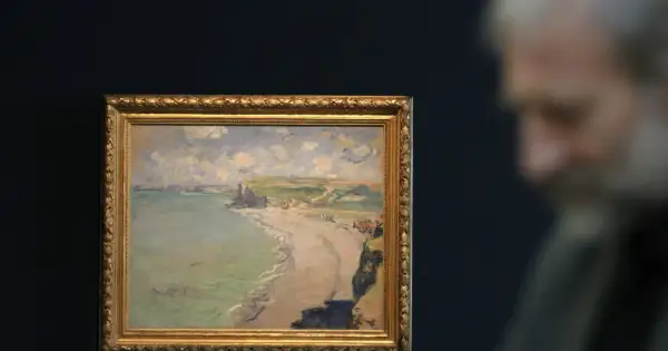Obraz przedstawia plażę w Pourville, z klifami i morzem w tle. W oddali widać sylwetkę mężczyzny.